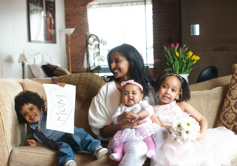 a woman sits with two children on a couch