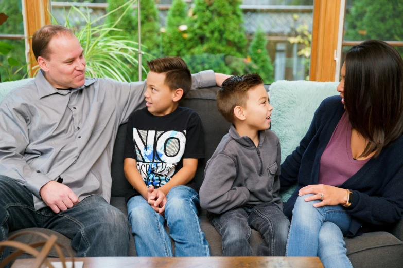 the man and children are sitting together on the couch