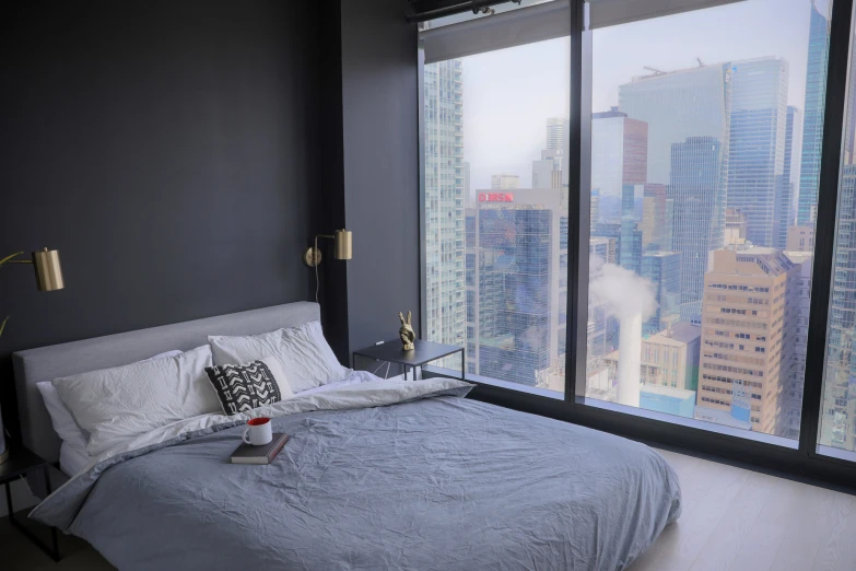 a bed sitting in front of a window next to a tall building
