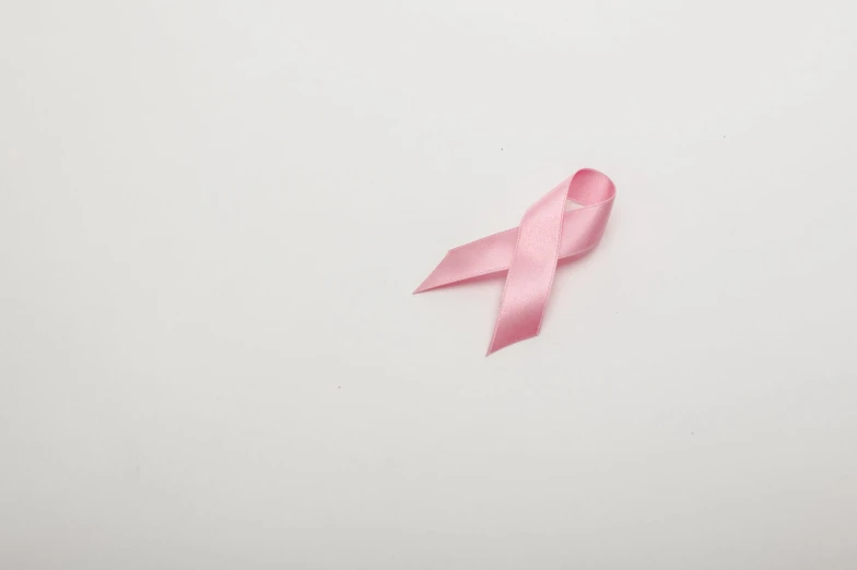 a light pink ribbon laying on top of a white surface