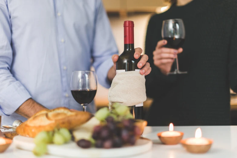 man pouring a glass of wine in front of food and candles