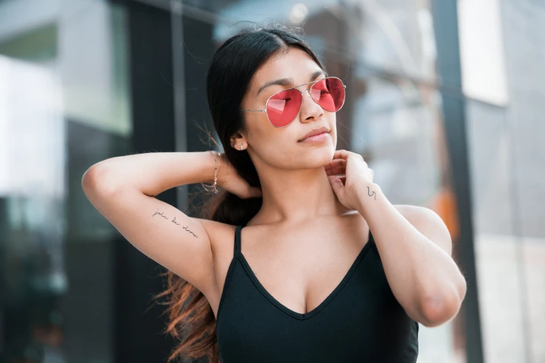 a beautiful young lady wearing sunglasses with tattoos on her arms