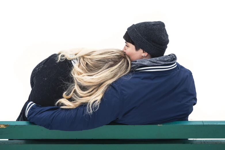 a man and woman sitting on a bench kissing