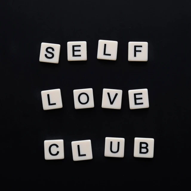 the words self love club written in small wooden letter blocks