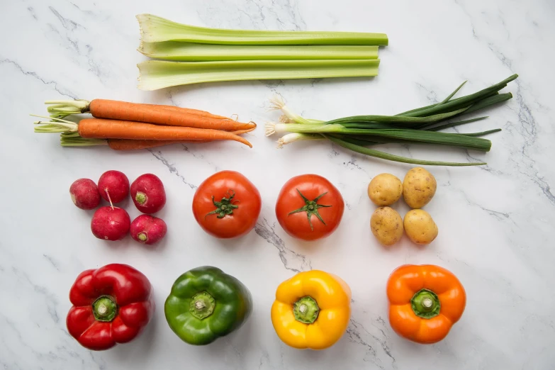 several different colored fruits and vegetables are on a white marble surface