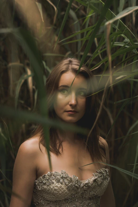 a woman is standing among grass in a dress