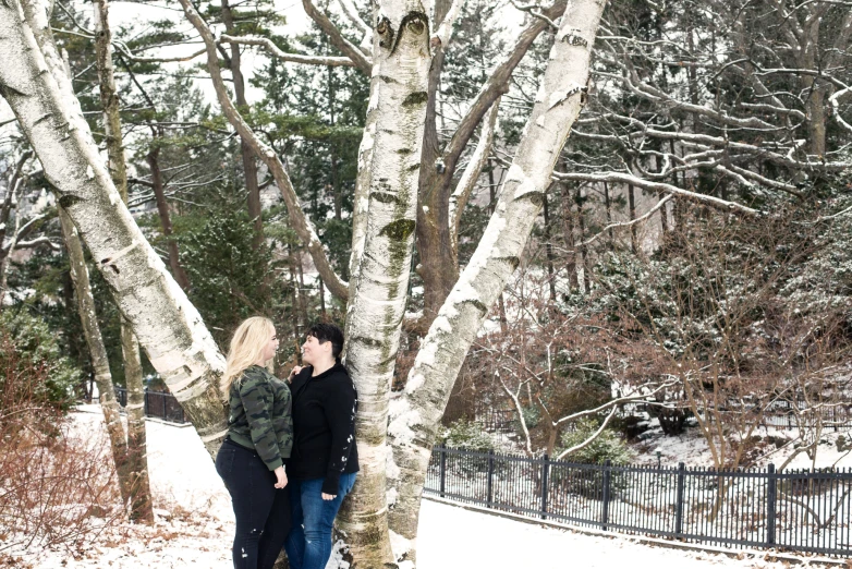 couple stand close next to each other by the trees