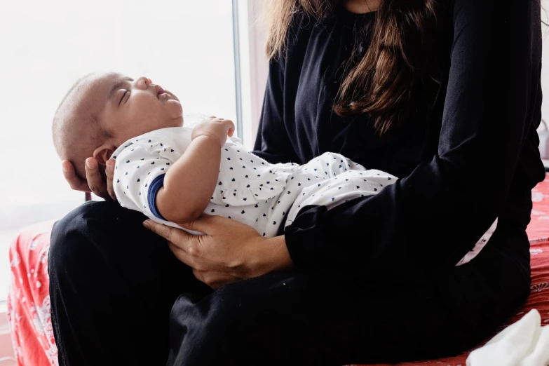 a young lady is holding her baby next to a window