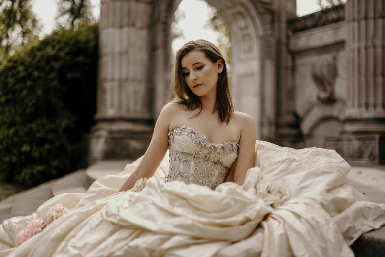 a woman sitting on the ground in a ball gown