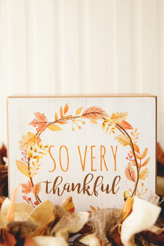 an wooden sign with a thanksgiving wreath and lettering