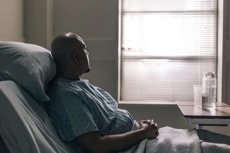 a man in a hospital gown sitting on a bed