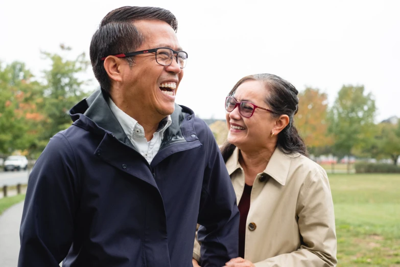 an asian man and woman in park walking next to each other