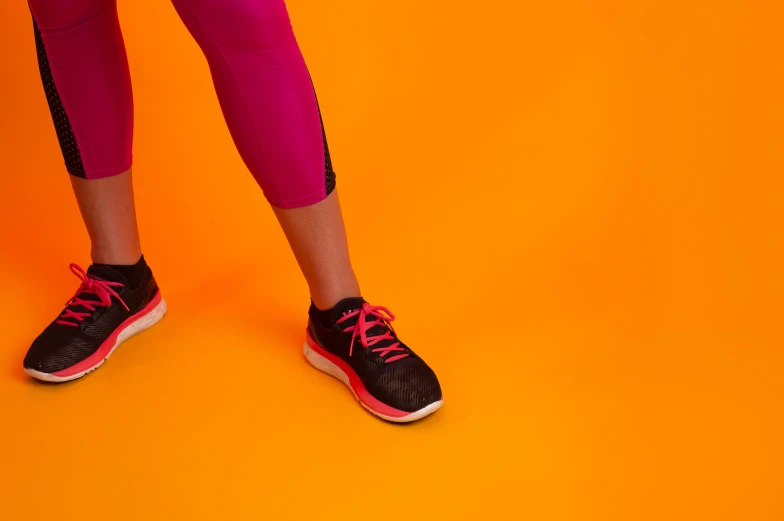 legs in pink tights and sneakers, on an orange background