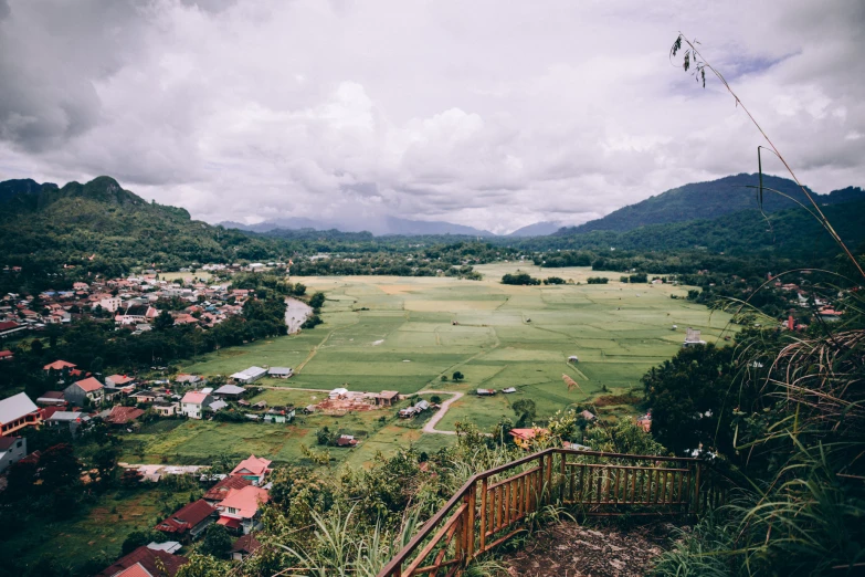 a lush green hillside surrounded by mountains under cloudy skies