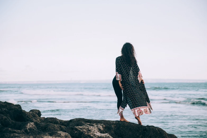 a woman standing on rocks overlooking the ocean