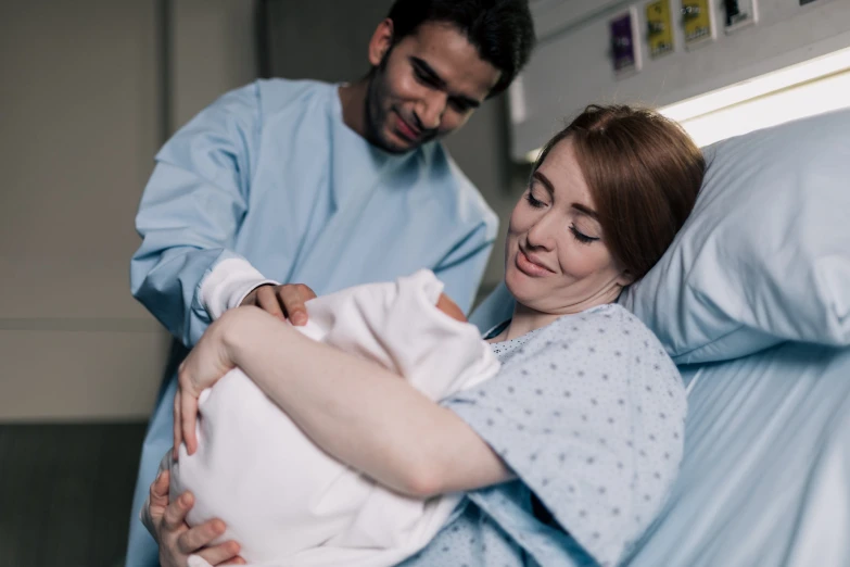 man and woman are in bed while holding a new born baby