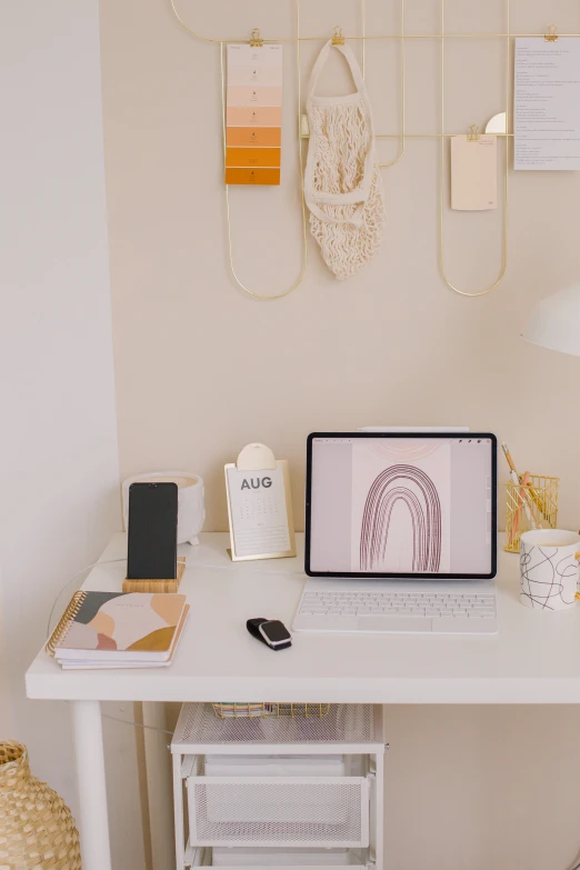 a laptop on a desk in the corner with several notes hanging from a hook on a wall above