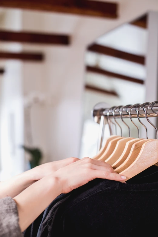 the woman's hand is holding on to a t - shirt rack