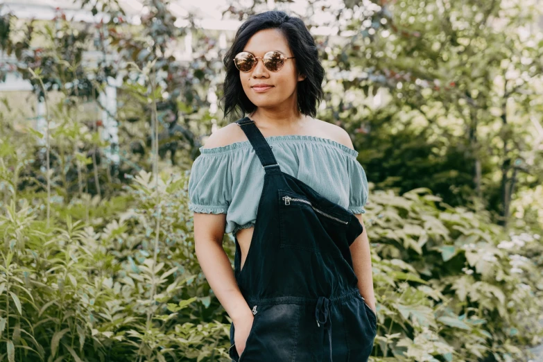 a woman stands among tall grass wearing sun glasses