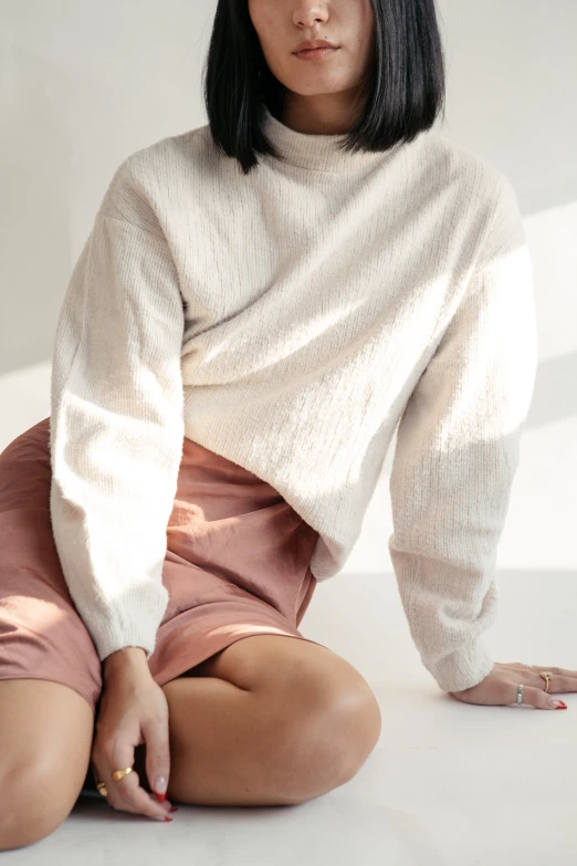 a woman sitting on the floor in front of white background