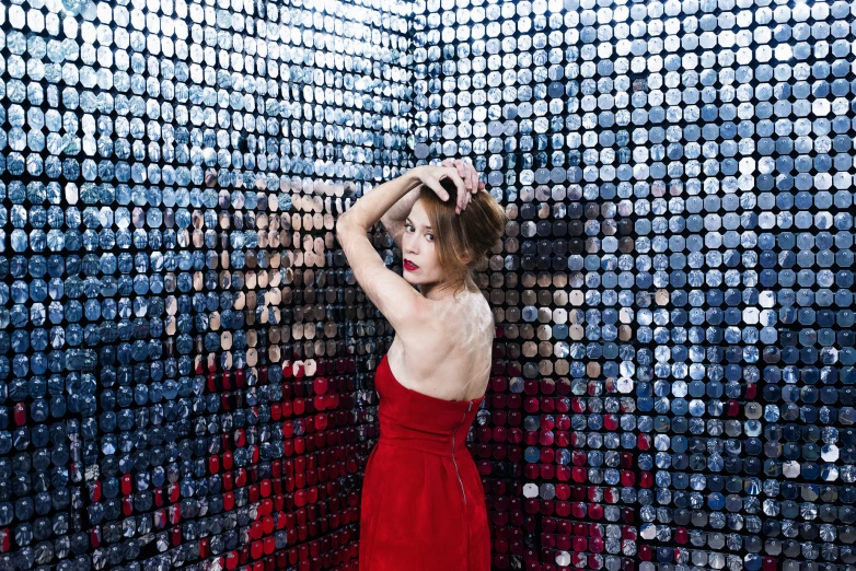 woman in a dress standing against a wall with many different colored squares