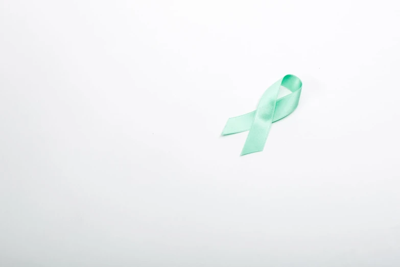 the green ribbon is laying on the white surface