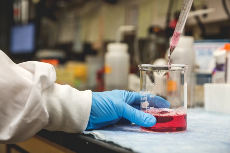 a hand holding a liquid sample filled with some pink liquid