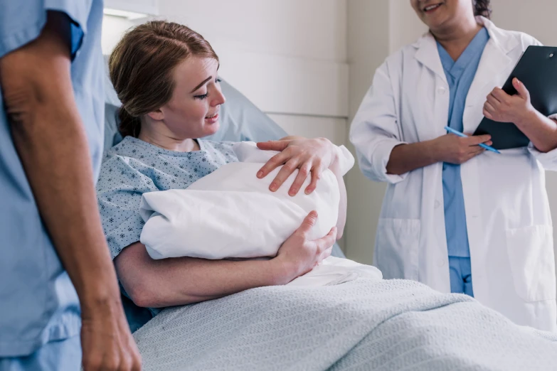 a woman in a hospital gown holds the stomach of another patient