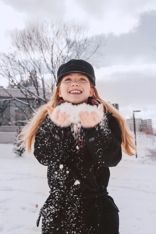 a woman standing in the snow holding her hands out to the camera