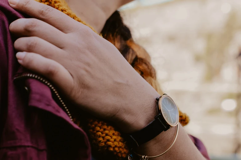 a close up view of a womans hand holding onto her gold watch