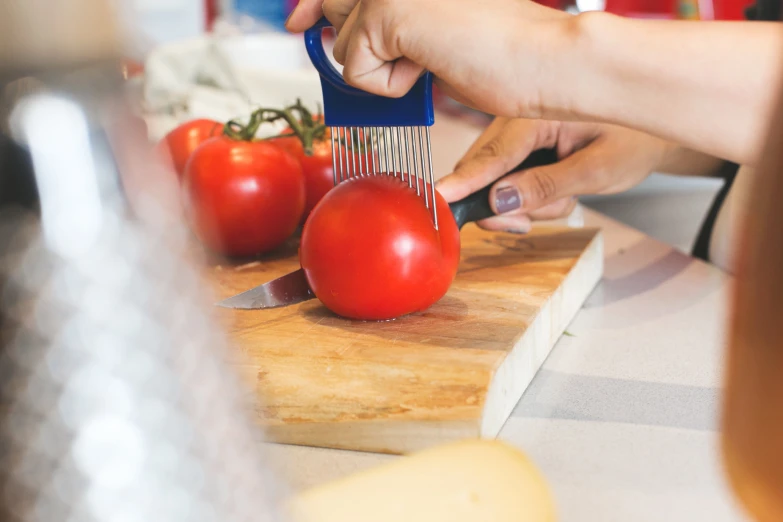 someone  up a tomato on a wooden board