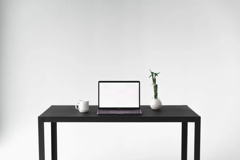 there is a laptop computer and two small vases on a table