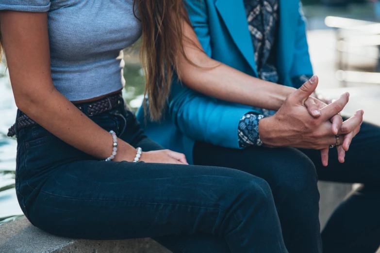 two women sitting on the ground having their hands clasped