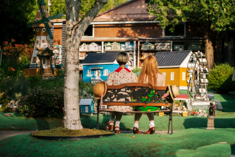 the children are sitting on the bench near the trees