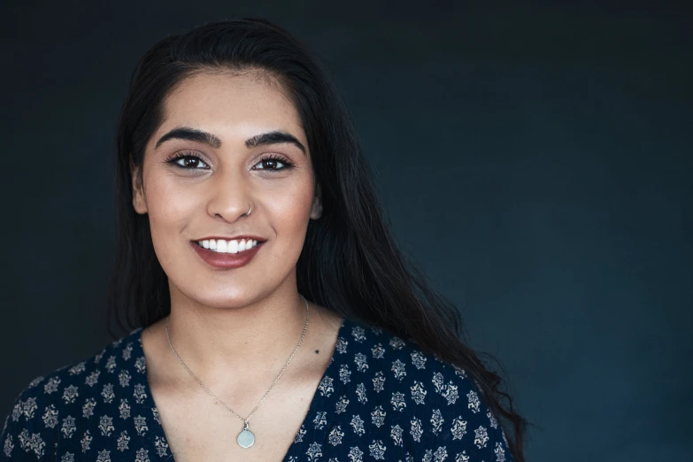 a smiling woman posing with dark background