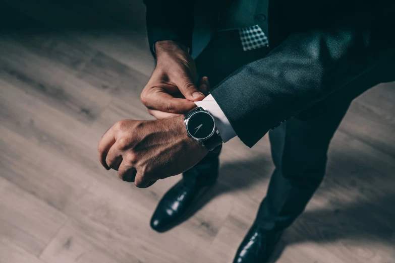 a man wearing a suit and tie is touching his watch