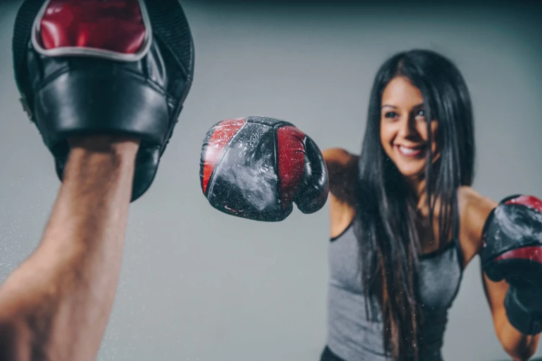 young woman with red boxing gloves near man holding his hand behind her