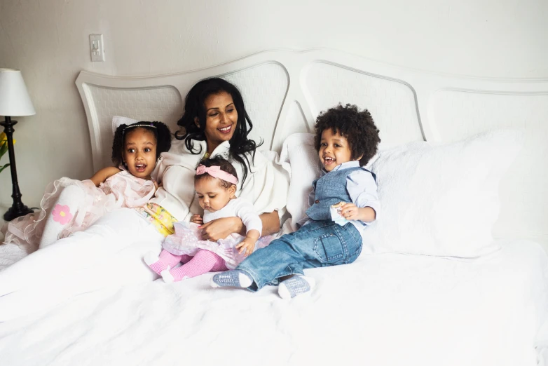 a woman lying in bed with two children