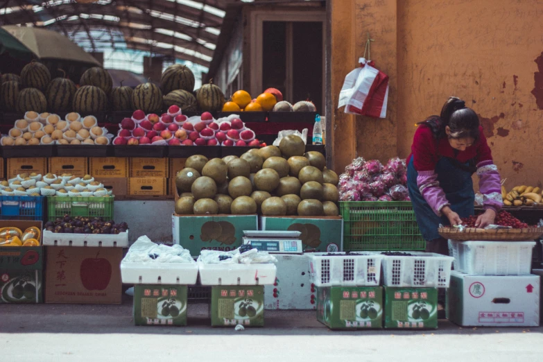 a woman is sitting in an outdoor produce stand