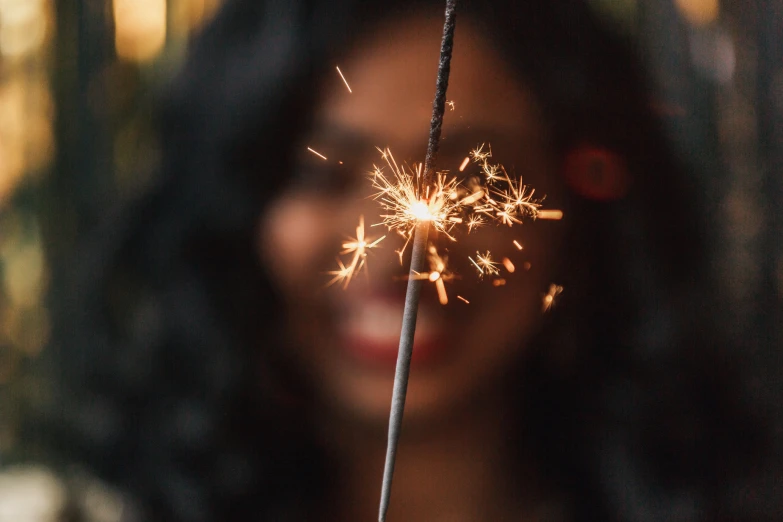 woman's face and long hair with sparkling sparkler in foreground