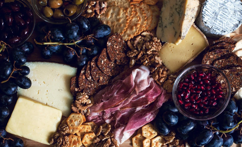 various types of cheese, meats, and fruit all spread out