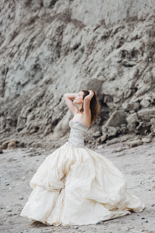 a beautiful young woman in a white dress standing on a beach