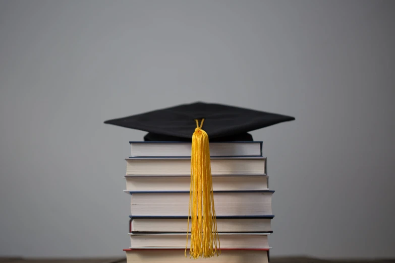 a stack of books with a graduation cap and tassel sitting on top