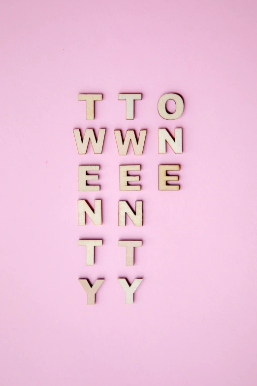 the word twenty spelled out in small wood letters on a pink surface