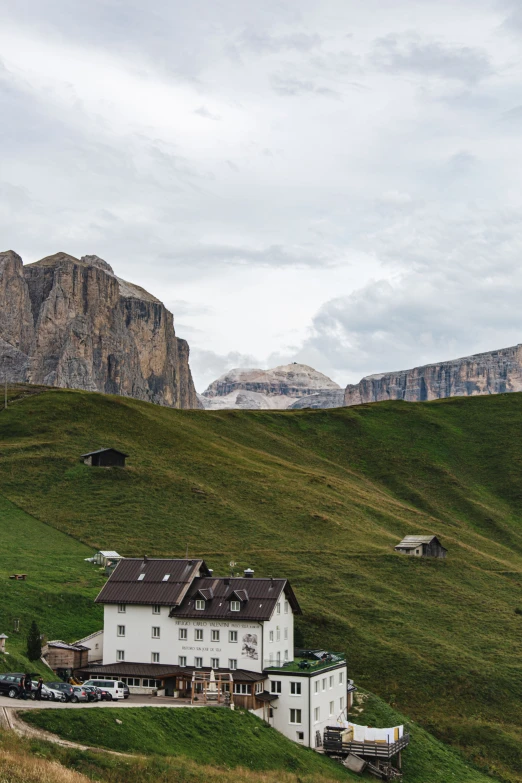 a house sitting on the side of a hill with cars parked below it