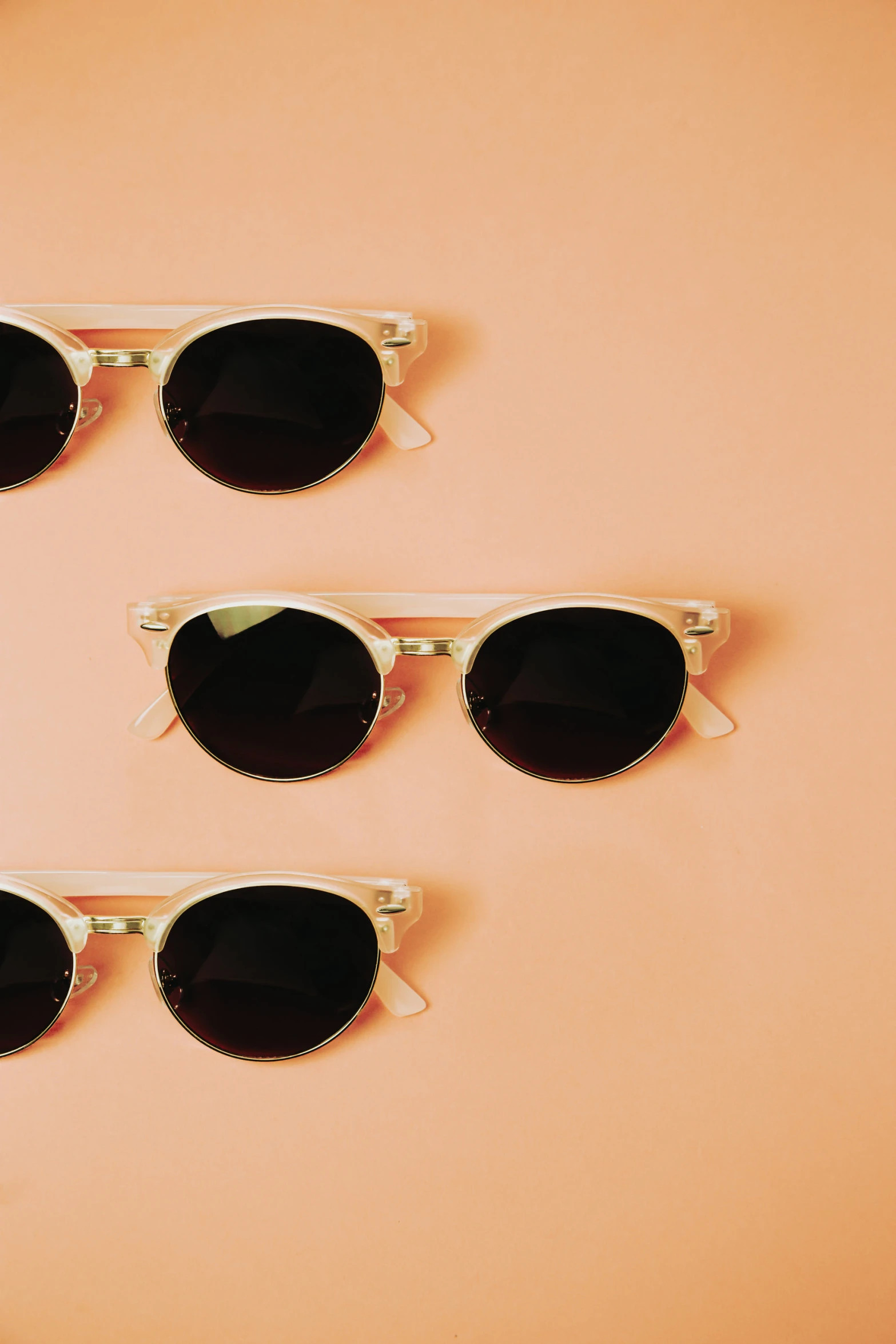 six sunglasses lying on top of a pink background