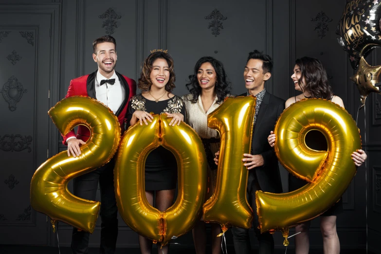 five people posing with golden balloons in front of a number 2013
