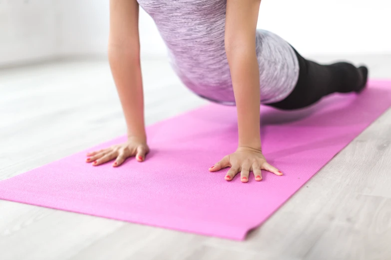 a girl who is on a pink mat doing h ups