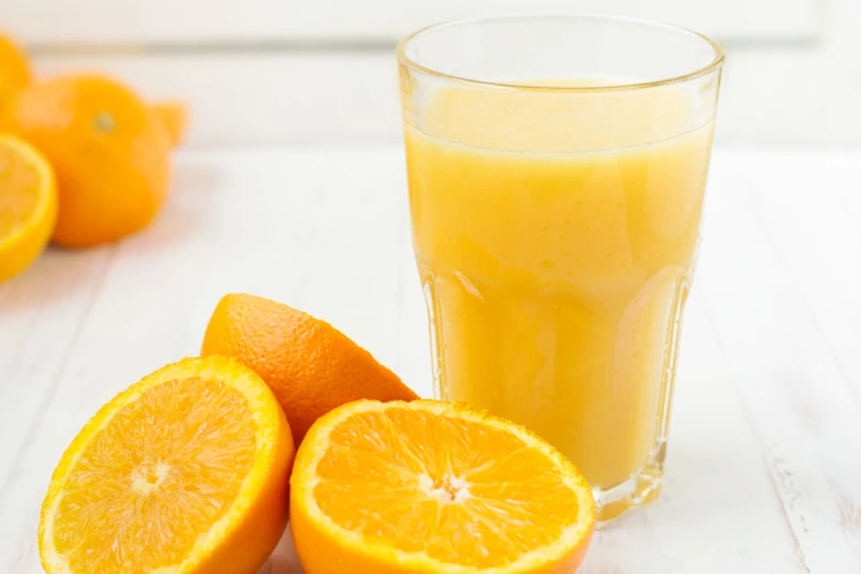 a glass full of orange juice next to oranges