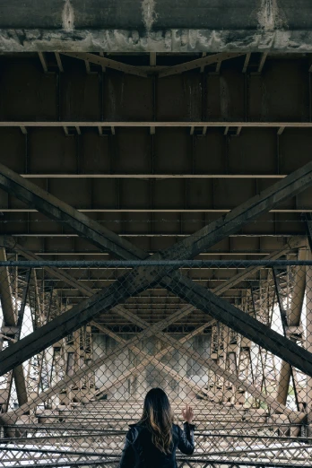 a woman standing underneath a long metal bridge